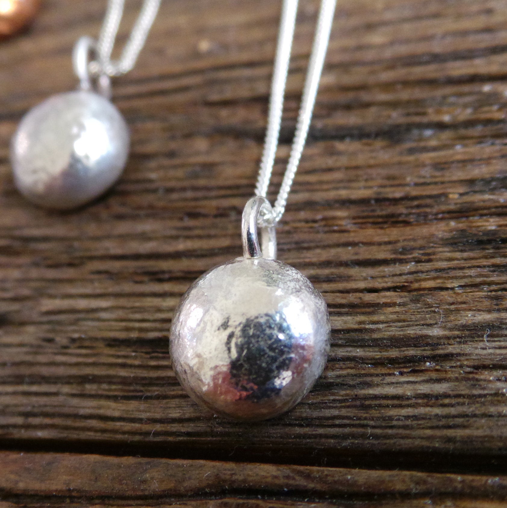 Round Silver pebble pendant hanging from a silver chain